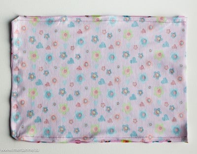 Kleines, bunt bedrucktes Stoffstück mit Blumen- und Herzmotiven, geeignet für Kinderkleidung oder Bastelprojekte, passend zum Thema Recycling für kleine Mädels.
