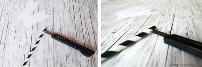 Schwarz-weiße gestreifte Papierfähnchen, Bastelwerkzeug und Marker auf Holzoberfläche, DIY Pflanzen-Fähnchen, einfache Bastelidee für Garten und Pflanzen.