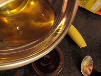 Flüssiger Reinigungsbalsam in einer Schüssel, ideal für die Ölreinigung, mit einem Löffel und weiteren Reinigungsprodukten im Hintergrund.