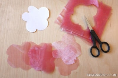 Schere, Organza-Stoffblumen und eine Schablone für kreative Bastelarbeiten mit Organza-Stoff, passend zur Anleitung für Blumen aus Organza.
