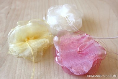 Bunte Blumen aus Organza-Stoff in Gelb, Weiß und Pink, ideal für Bastel- und Nähprojekte, handgemacht, kreative Dekorationen, leicht zu bearbeiten.