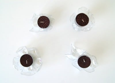 Vier Kunststoff-Buttons in Blütenform, die als kreative Dekoration oder Upcycling-Elemente verwendet werden können.