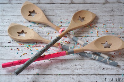 Vier handgefertigte Holzlöffel mit Sternausschnitt, dekoriert mit bunten Streifen und Konfetti, ideal für kreative Küchenprojekte und nachhaltiges Kochen.