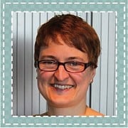 Lächelnde Frau mit kurzen braunen Haaren und Brille, professionelles Porträt für HANDMADE Kultur, Fokus auf Handwerkskunst und Kreativität.