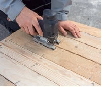 Handwerker schneidet Holzpalette mit Stichsäge für ein DIY Küchenregal aus Paletten, kreative Upcycling-Idee für nachhaltige Einrichtung.
