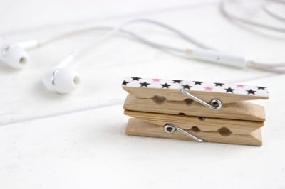 Kleine Holzklammern mit Sternenmuster halten Kopfhörerkabel ordentlich zusammen, verhindern Kabelsalat in der Handtasche, praktische DIY-Lösung für Kabelorganisation.