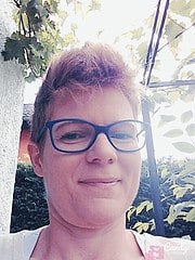Porträt einer Frau mit Brille, die im Garten steht, umgeben von grünen Blättern, für Handmade Kultur, kreative Handwerkskunst, DIY, nachhaltige Produkte, Kunsthandwerk, individuelle Gestaltung.