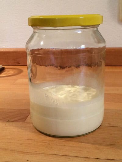 Frisch hergestellte Butter in einem Glas mit gelbem Deckel, bereit zum Verzehr oder zur Weiterverarbeitung.