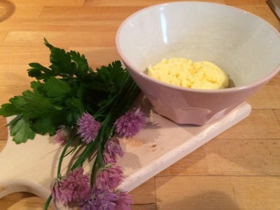 Frische Kräuter und selbstgemachte Butter in einer Schüssel, ideal für hausgemachte Butterrezepte.