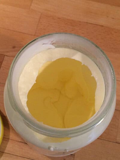 Frisch hergestellte Butter in einem Glas, sichtbar mit flüssigem Fett an der Oberfläche, ideal für hausgemachte Butterrezepte.