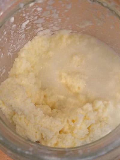 Frisch hergestellte Butter in einem Glasbehälter, cremig und gelb, ideal für hausgemachte Butterrezepte, passend zum Beitrag "Butter ganz einfach selbstgemacht…".