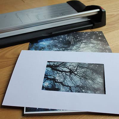 Fotografie einer Glückwunschkarte mit Passepartout, die einen winterlichen Baum im Hintergrund zeigt, auf einem Holz Tisch, für kreative Grußkarten aus alten Zeitschriften.