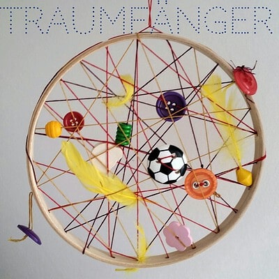 Kreativer Traumfänger mit bunten Knöpfen, Federn und Schnüren, passend zum Thema Traumfänger mal anders, für eine kreative Raumdekoration.