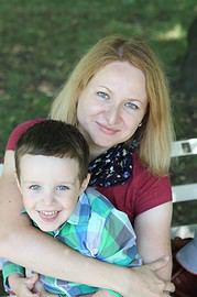 Lächelnde Mutter und Sohn beim gemeinsamen Moment im Park, umgeben von Natur, mit Fokus auf Familienzeit und Outdoor-Aktivitäten.