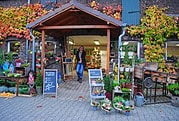 Handmade Kultur Kreativmarkt mit handgemachten Produkten, Pflanzen und Dekorationen, im Eingangsbereich eines charmanten Gebäudes mit Herbstlaub und liebevoll gestalteten Ständen.