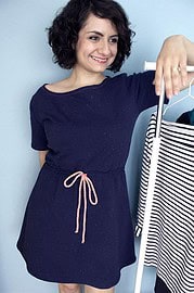 Frau beim Anziehen eines gestreiften Kleidungsstücks, kreative Handarbeit, nachhaltige Mode, DIY, Modeaccessoires, umweltfreundliche Textilien, Modekunst, Handarbeit, Mode-Design, kreative Kleidung.