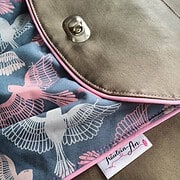 Handgefertigte Tasche mit Vogelmuster in Pastellfarben, mit Metallverschluss und pinkem Ziernähten, ideal für nachhaltigen und stilvollen Alltag.