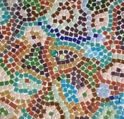 Detail eines Mosaik-Kunstwerks mit bunten Glas- und Keramikfliesen in verschiedenen Farben und Mustern, handgefertigt für kreative Dekorationen.