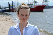 Junge Frau am Hafen mit Booten im Hintergrund, symbolisiert kreative Handarbeit und nachhaltiges Handwerk, passend für Handmade Kultur.