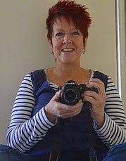 Frau mit roten Haaren und gestreiftem Oberteil hält Kamera und fotografiert sich selbst, kreative Darstellung für Handmade Kultur.