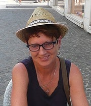 Frau mit Brille und Strohhut, lächelnd, bei Handmade Kultur Veranstaltung, kreative Handwerkskunst, sommerliche Atmosphäre, outdoor Event, Kunst und Handarbeit.