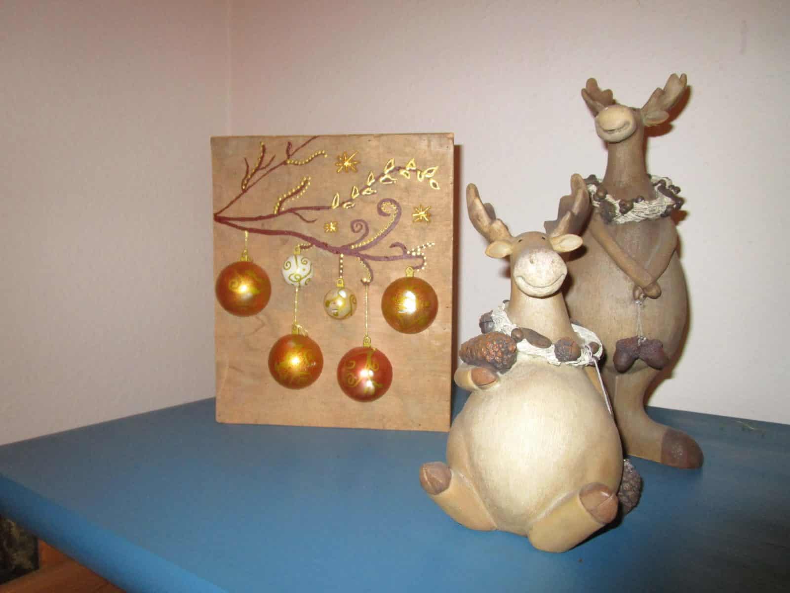 Beleuchtetes Bild mit Weihnachtskugeln auf Holz