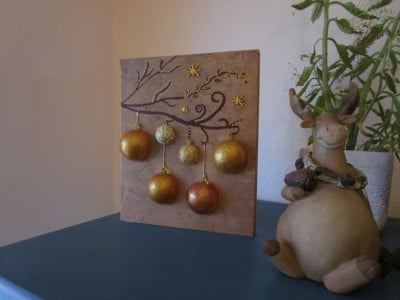 Beleuchtetes Bild mit Weihnachtskugeln auf Holz