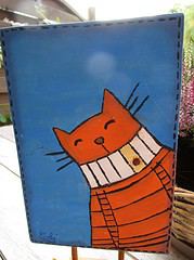 Handgemaltes Bild einer lachenden Katze mit orangefarbenem Streifenmuster, das kreative und handgemachte Kunstwerke für die HANDMADE Kultur präsentiert.