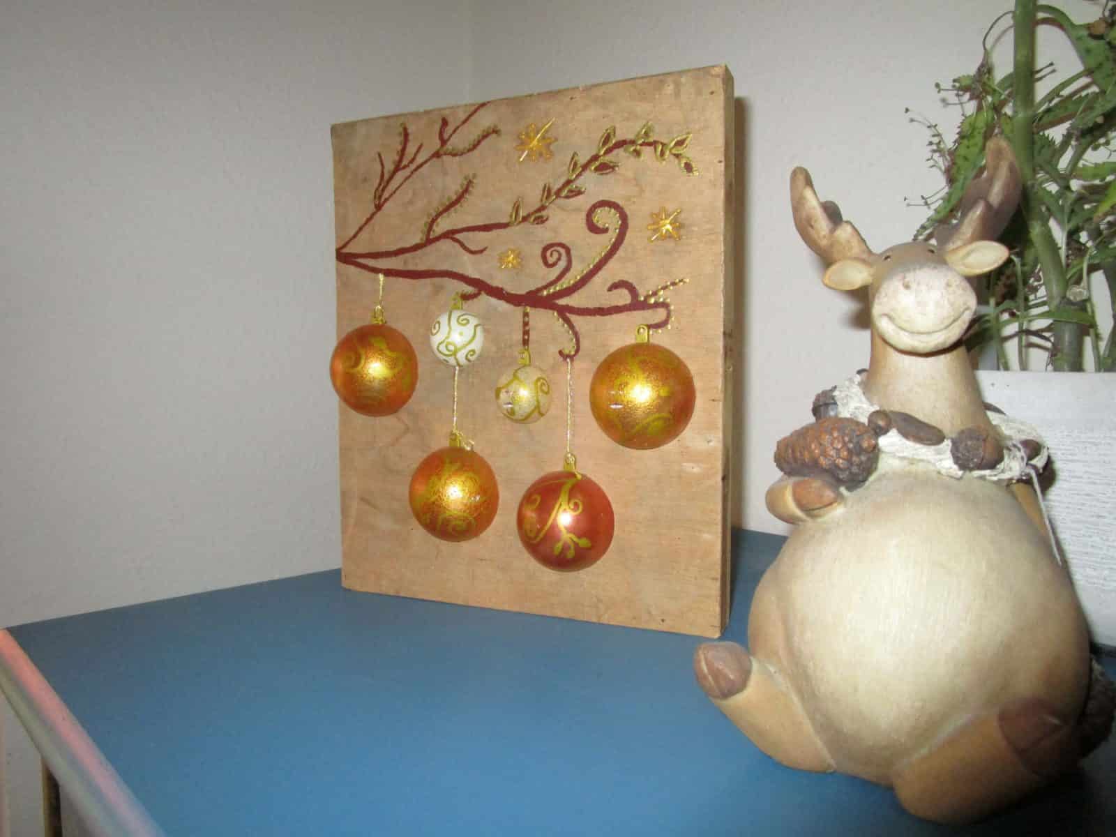 Beleuchtetes Bild mit Weihnachtskugeln auf Holz