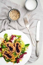 knusprig gebratene Rotkraut Roulade aus Kartoffel-Rote Beete Teig auf einem Bett aus Salat