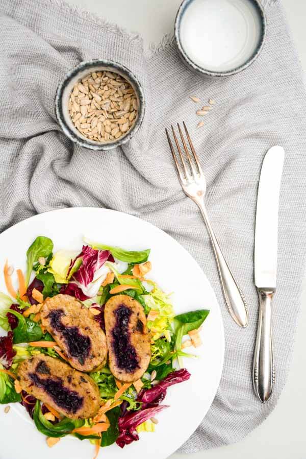 knusprig gebratene Rotkraut Roulade aus Kartoffel-Rote Beete Teig auf einem Bett aus Salat