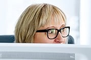 Frau mit Brille arbeitet konzentriert an einem Computer, umgeben von kreativen handgemachten Produkten bei HANDMADE Kultur.