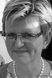 Schönes Porträt einer Frau mit kurzen, gestylten Haaren, Brille und Perlenkette, passend für handgemachte Kultur und kreative Handwerkskunst.