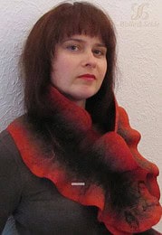 Frau mit dunklem Haar trägt roten, handgefertigten Schal, präsentiert bei Handmade Kultur, Fokus auf kreative Textilkunst und nachhaltiges Handwerk.