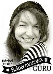 Bärbel Born, eine kreative Handwerkerin, lächelt herzlich, während sie an ihren selbstgemachten Kunstwerken arbeitet, die für Handmade Kultur stehen.