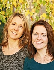 Zwei Frauen lächeln in einem Naturhintergrund mit gelben Blättern, symbolisiert Kreativität und Handwerkskunst bei Handmade Kultur.