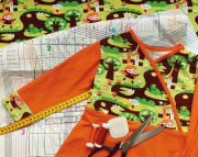 Bunte Kinderjacke mit Tiermotiven, Nähzubehör und Maßband für handgemachte Kleidung, Fokus auf kreative Mode für Kinder bei HANDMADE Kultur.