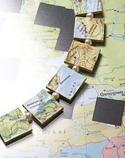 Karten und kleine Perlen auf einer Landkarte, symbolisieren Reiseplanung und kreative Gestaltung von Reisezielen.