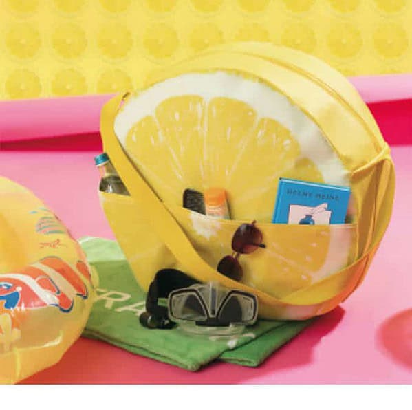 Bunte Zitronen-Tasche mit Sonnenbrille, Sonnencreme, Buch und Strandspielzeug, perfekt für den Sommerurlaub oder den Strand.
