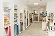 Stoffregale mit bunten Stoffen und Nähzubehör in einem kreativen Handarbeitsladen, ideal für handgemachte Textilprojekte und Näharbeiten.