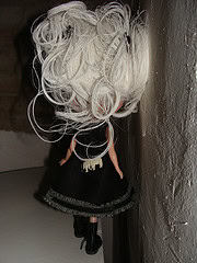 Puppenfigur mit weißen, lockigen Haaren, schwarzem Kleid und schwarzen Schuhen, handgefertigt, ideal für kreative Bastelprojekte und Dekorationen.