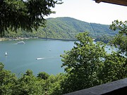 Idyllischer Blick auf einen See mit Booten, umgeben von grünen Bergen und Bäumen, perfekte Kulisse für Natur- und Outdoor-Aktivitäten.