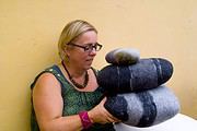 Frau mit Brille und buntem Armband hält eine Skulptur aus gefilzten Wollstücken bei HANDMADE Kultur, Fokus auf kreative Handwerkskunst und Textilkunst.