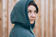 Frau trägt eine modische, graue Kapuzenjacke, die für nachhaltige und handgemachte Mode steht, perfekt für umweltbewusste Modefans.