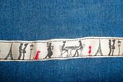Handgefertigte Stickerei mit antiken Figuren und roten Akzenten auf Stoffstreifen, zeigt traditionelle Handwerkskunst und kulturelle Details.