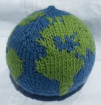 Handgefertigte Weltkugel aus grüner und blauer Wolle, symbolisiert globale Nachhaltigkeit und Umweltbewusstsein, ideal für umweltbezogene Handwerkskunst und Dekoration.