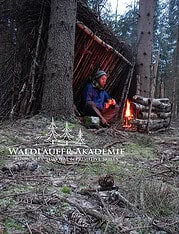 Person sitzt am Lagerfeuer in Wald, unter einem selbstgebauten Unterschlupf, umgeben von Bäumen, beim Bushcraft-Training, Fokus auf Naturverbundenheit und primitive Fähigkeiten.