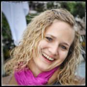 Fröhliche Frau mit lockigem Haar, pinkem Schal und natürlichem Lächeln, bei Handmade Kultur Veranstaltung, authentisch und kreativ, für SEO optimiert.