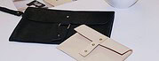 Zwei handgefertigte Lederetuis in Schwarz und Beige, ideal für Dokumente und Stifte, präsentiert auf einer weißen Oberfläche, betont die hochwertige Handwerkskunst und das elegante Design.