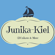 Logo von Junika-Kiel mit Segelschiff und Meeresmotiv, repräsentiert handgemachte maritime Produkte und kreative Handwerkskunst aus Kiel.